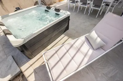 a bath tub with a chair and a table at Richgood Luxury homes - Villa Zefira mare in Altavilla Milicia