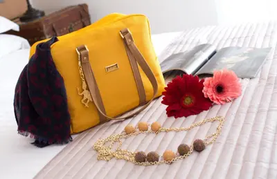 a yellow purse and a red flower on a bed at Suite 136 in Palermo