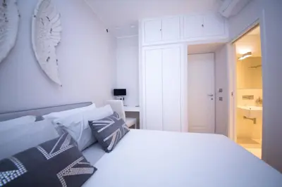 a white bedroom with a white bed with pillows at Suite 136 in Palermo