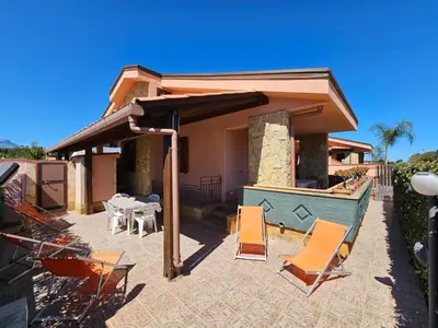 a house with a patio with chairs and a grill at Holiday Home Helle mediterrane Villa mit Veranda und Garten by Interhome in Cefalù