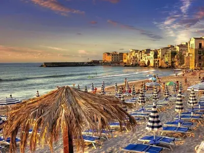 a beach with chairs and umbrellas and the ocean at Holiday Home Helle mediterrane Villa mit Veranda und Garten by Interhome in Cefalù