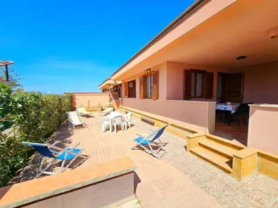 a patio with chairs and tables on a house at Holiday Home Helle mediterrane Villa mit Veranda und Garten by Interhome in Cefalù