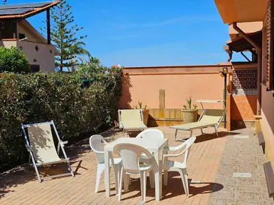 a patio with a table and chairs on a brick patio at Holiday Home Helle mediterrane Villa mit Veranda und Garten by Interhome in Cefalù