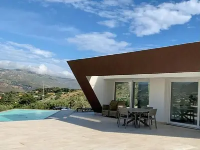 a house with a patio with a table and chairs at Sustainable Villa With Infinity Pool in Castellammare del Golfo