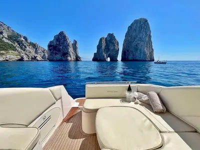 a boat on the water with rocks in the water at Palermo Boat Experience in Isola delle Femmine