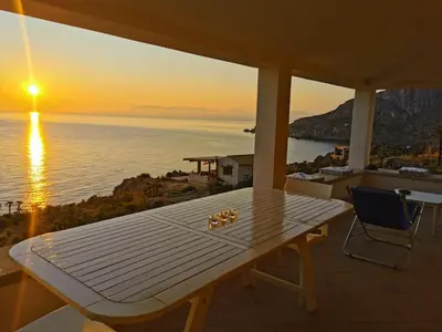 a table and chairs on a balcony with the sunset at Chalet Le Palmette in Contrada Sauci Grande