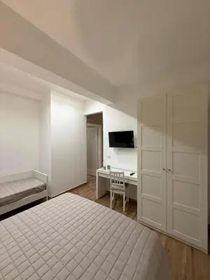 a white bedroom with a bed and a desk at Titti's Nest in Casteldaccia