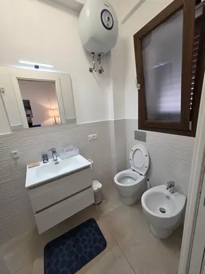 a bathroom with a sink and a toilet and a mirror at Francesca Holiday Home in Castellammare del Golfo