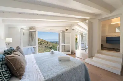 a bedroom with a large bed and a large window at Villa Baja Scopello in Balata di Baida