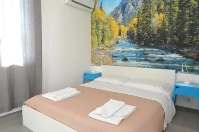 a bedroom with a bed with a painting of a river at Casa Verdemare in Cefalù