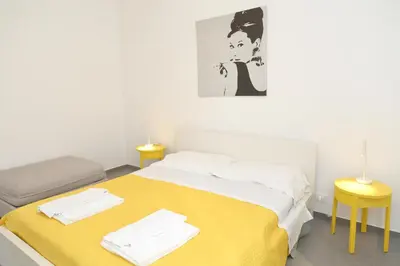 a bedroom with a bed with a yellow blanket and two tables at Casa Verdemare in Cefalù
