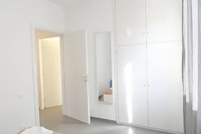 a white bedroom with white cabinets and a mirror at Casa Verdemare in Cefalù