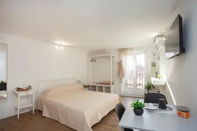 a white bedroom with a bed and a table at Vicoloft al Capo in Palermo
