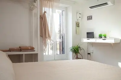 a white bedroom with a bed and a window at Vicoloft al Capo in Palermo