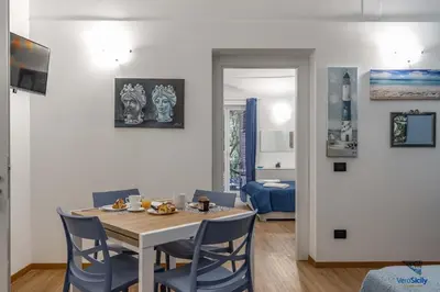 a dining room with a table and blue chairs at Al Mondellu apt Verosicily in Palermo