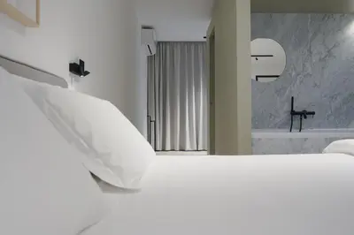 a white bedroom with a bed and a bath tub at Idro Luxury Suite in Palermo