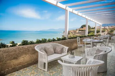 a patio with chairs and tables and a view of the ocean at Hotel Tonnara Trabia in Trabia