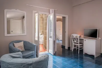 a living room with a chair and a table and a television at Hotel Tonnara Trabia in Trabia