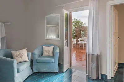 a living room with a blue chair and a mirror at Hotel Tonnara Trabia in Trabia