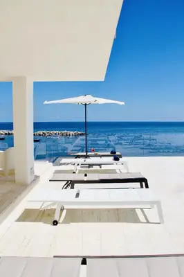 a group of tables with an umbrella and the ocean at Hotel Tonnara Trabia in Trabia