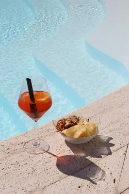 a drink and a bowl of food next to a pool at Hotel Tonnara Trabia in Trabia