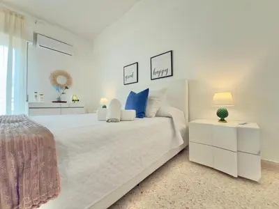 a white bedroom with a large white bed with blue pillows at Merlo Holiday Homes Attico in Palermo