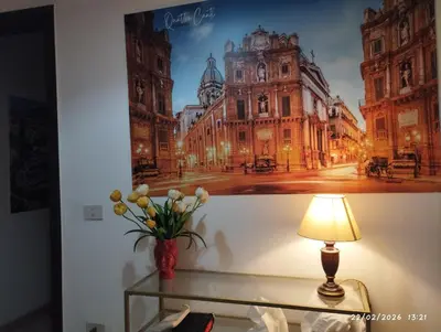 a vase of flowers on a table next to a picture of a street at Nanà in Movida in Palermo