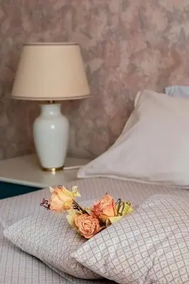 a bouquet of flowers on a bed with a lamp at Agelina square Home Gibellina in Nuova Gibellina