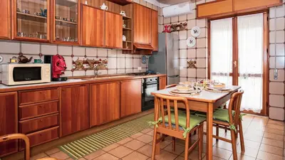 a kitchen with wooden cabinets and a table with chairs at Agelina square Home Gibellina in Nuova Gibellina
