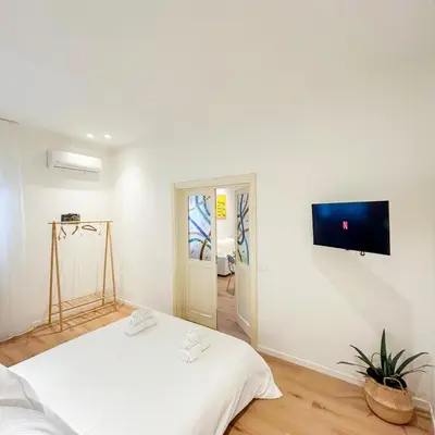 a white room with a bed and a tv on the wall at Palazzo Crisafulli Suite in Palermo