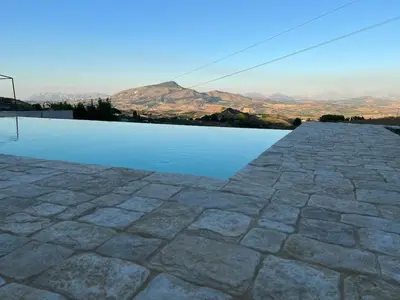 a pool of water with mountains in the background at RossoScirì in Calatafimi