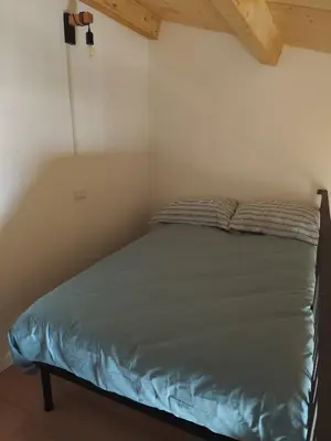 a bed in a small room with a wooden ceiling at Appartamento La Perla bianca in Palermo