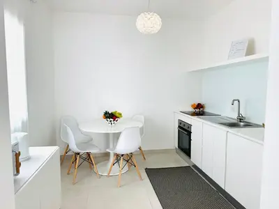 a white kitchen with a white table and chairs at Casa Battigia in Alcamo