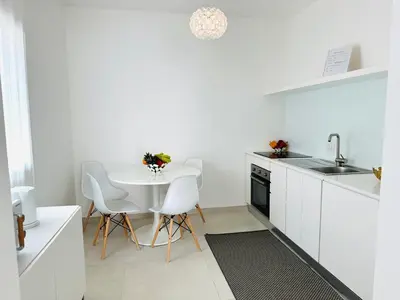 a white kitchen with a white table and chairs at Casa Battigia in Alcamo