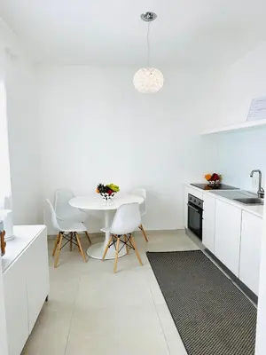 a white kitchen with a table and white chairs at Casa Battigia in Alcamo