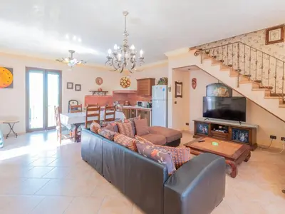 a living room with a couch and a kitchen and stairs at Casa San Nicola Trabia Mare in Trabia