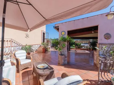 a patio with chairs and tables and an umbrella at Casa San Nicola Trabia Mare in Trabia
