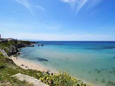 a beach with people swimming in the water at Apartment Wohnung dei Mori in Terrasini by Interhome in Terrasini