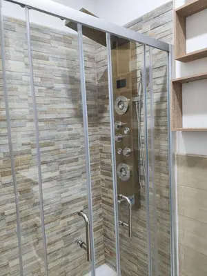 a shower in a bathroom with a stone wall at Heidi's home in Villabate