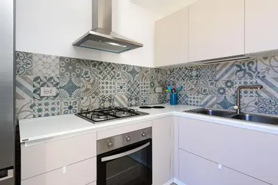 a kitchen with white cabinets and a stove and sink at A Casa Di Vale in San Vito lo Capo