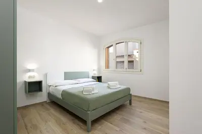 a white bedroom with a bed and a window at A Casa Di Vale in San Vito lo Capo