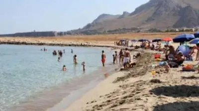 a group of people on a beach in the water at L' arcobaleno in Castelluzzo