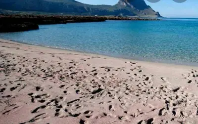 a beach with a bunch of rocks in the sand at L' arcobaleno in Castelluzzo