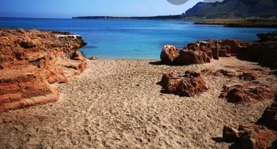 a beach with some rocks and the water at L' arcobaleno in Castelluzzo