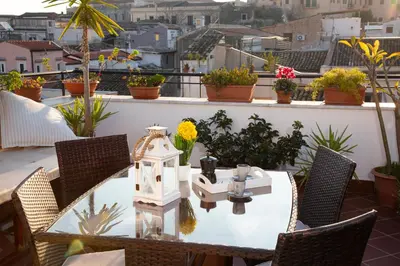 a table and chairs on a balcony with flowers at Apartment Papyri in Palermo