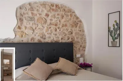 a bedroom with a bed with a stone wall at Curina Boutique Stay - Luxury Villa in the Sicilian Countryside in Castellammare del Golfo