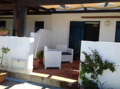a patio with white walls and a chair and a table at Paradiso Isulidda in Macari