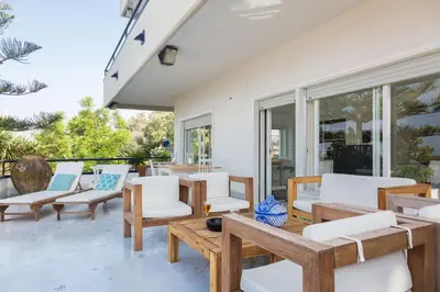 a patio with white chairs and tables and windows at White and Sea Villa fronte mare a Mondello Addaura in Palermo