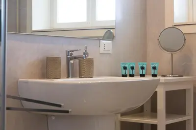a white sink in a bathroom with a mirror at White and Sea Villa fronte mare a Mondello Addaura in Palermo