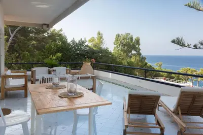 a patio with a table and chairs and the ocean at White and Sea Villa fronte mare a Mondello Addaura in Palermo